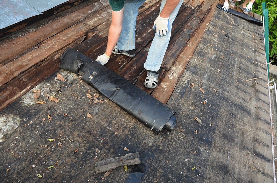 Old Roof Repair And Renovation. A Man Is Removing Old Bitumen Or Storm Damage Repairs